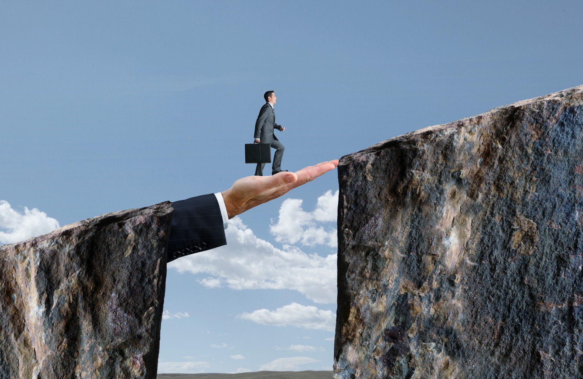 Businessman Walking On Hand That Bridges The Gap