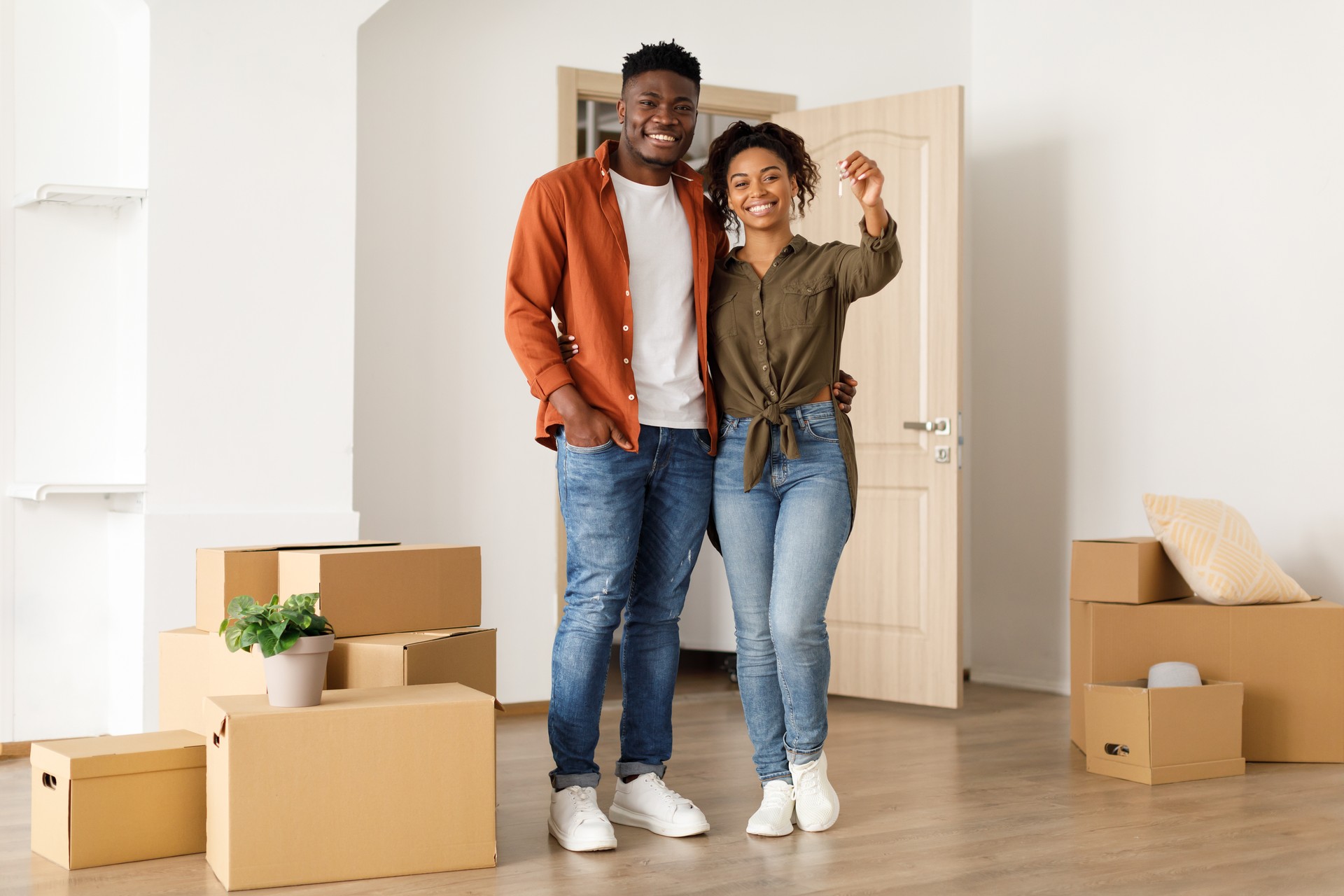 Joyful Black Couple Showing Key Standing In New House