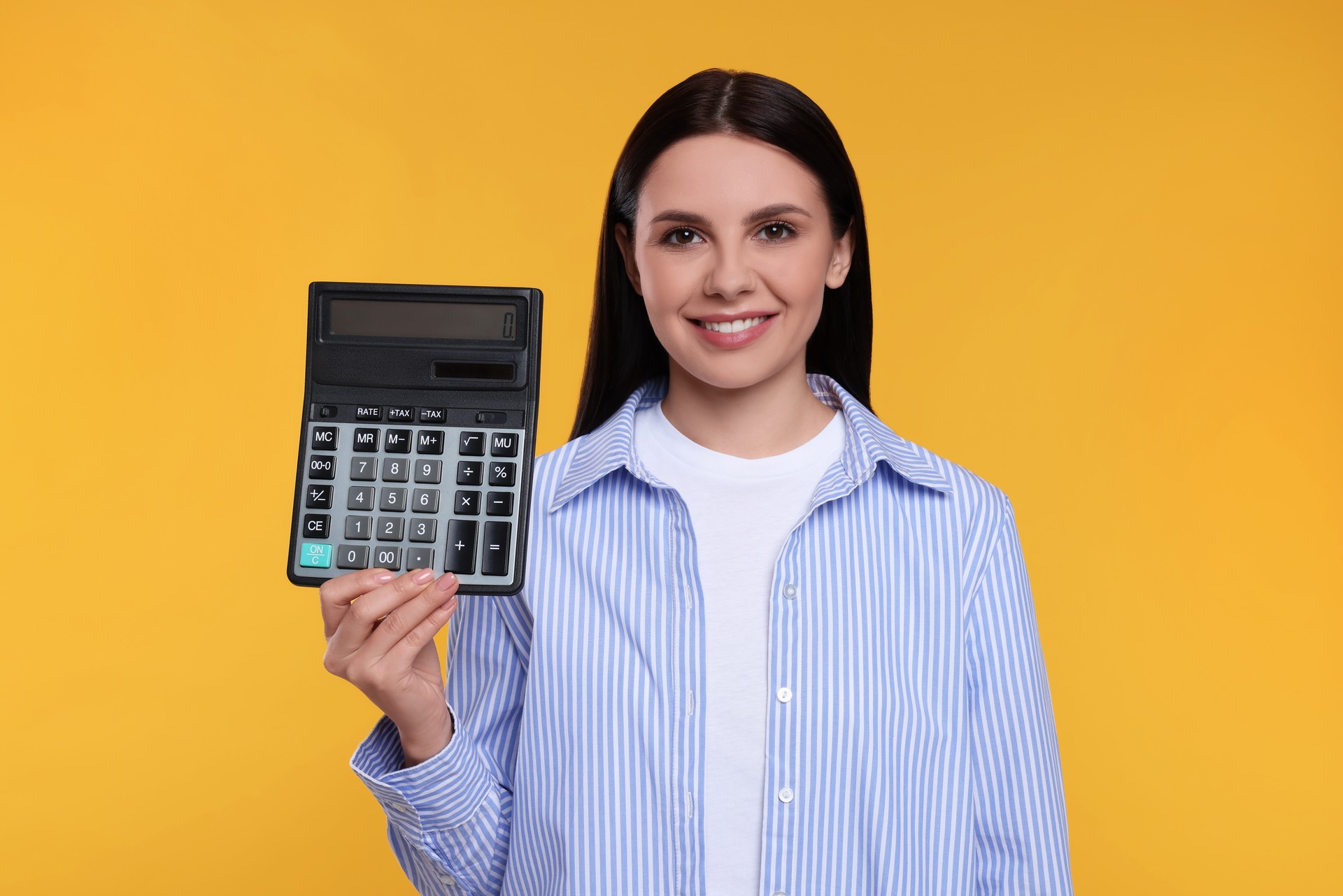 Smiling accountant with calculator on yellow background